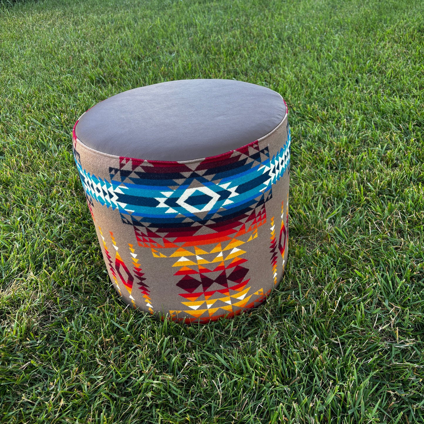 Handmade ottoman placed on grass outdoors, showcasing Pendleton Pilot Rock fabric with blue, red, and gold patterns