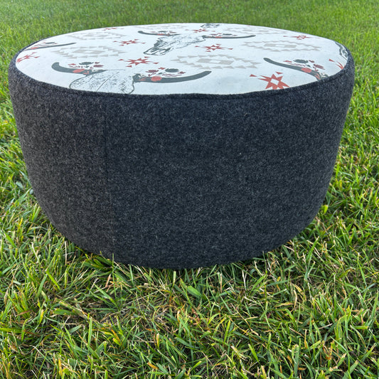 Side angle of ottoman on grass showing black wool texture and round shape
