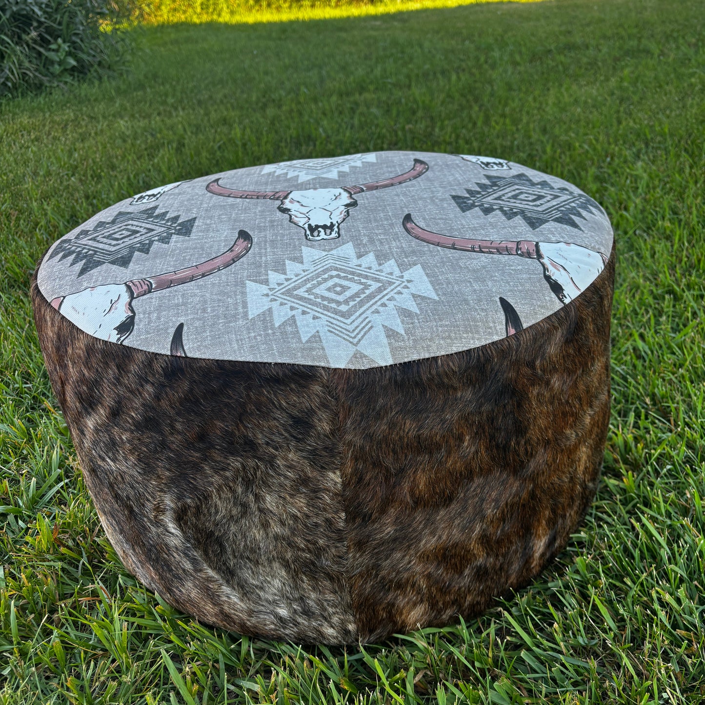Angled outdoor view of brindle cowhide ottoman with tribal design