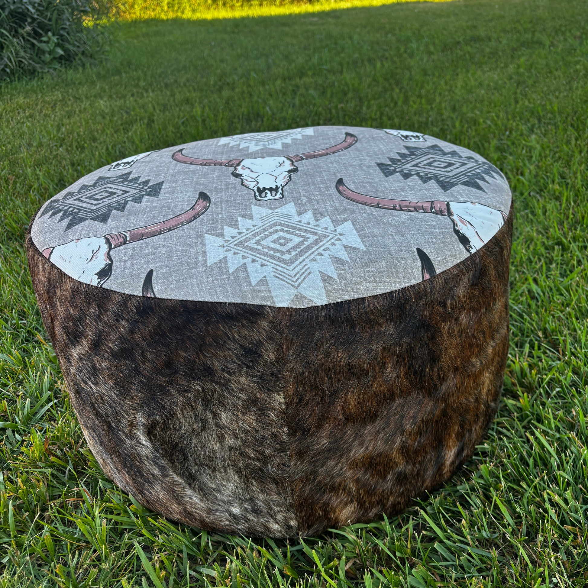 Angled outdoor view of brindle cowhide ottoman with tribal design