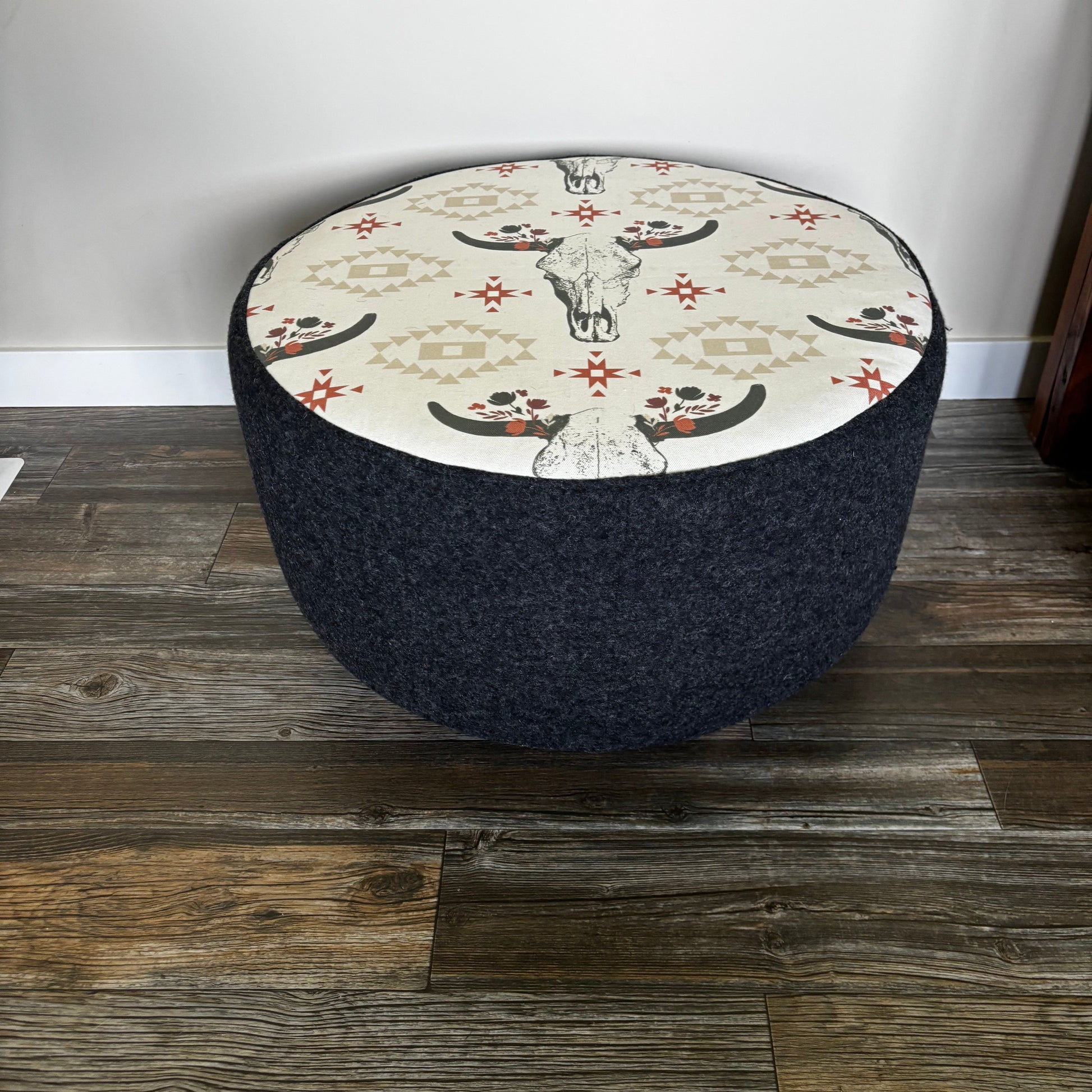 Angled view of round cow skull ottoman with Western-style print and black wool fabric