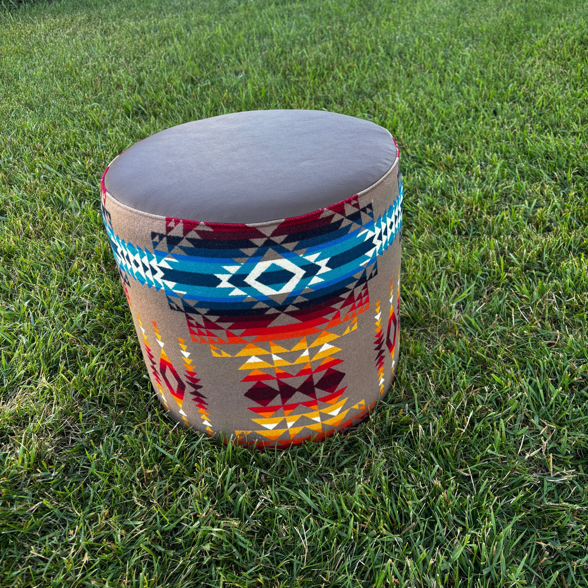Handmade ottoman placed on grass outdoors, showcasing Pendleton Pilot Rock fabric with blue, red, and gold patterns