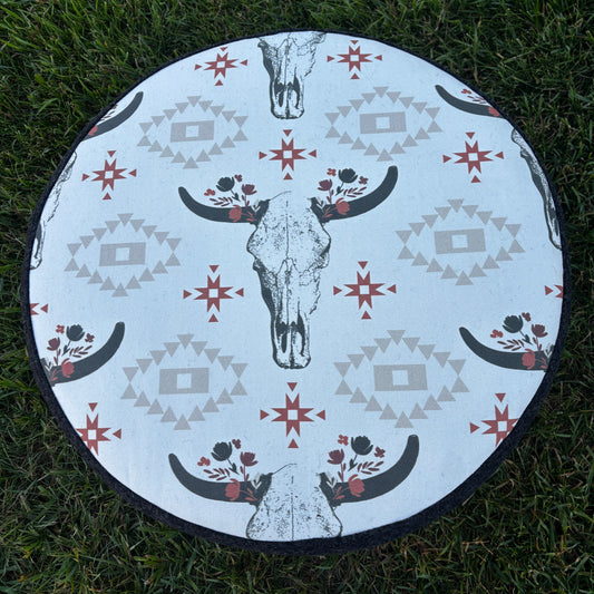 Outdoor view of ottoman top with rustic cow skull and Southwestern print on grass