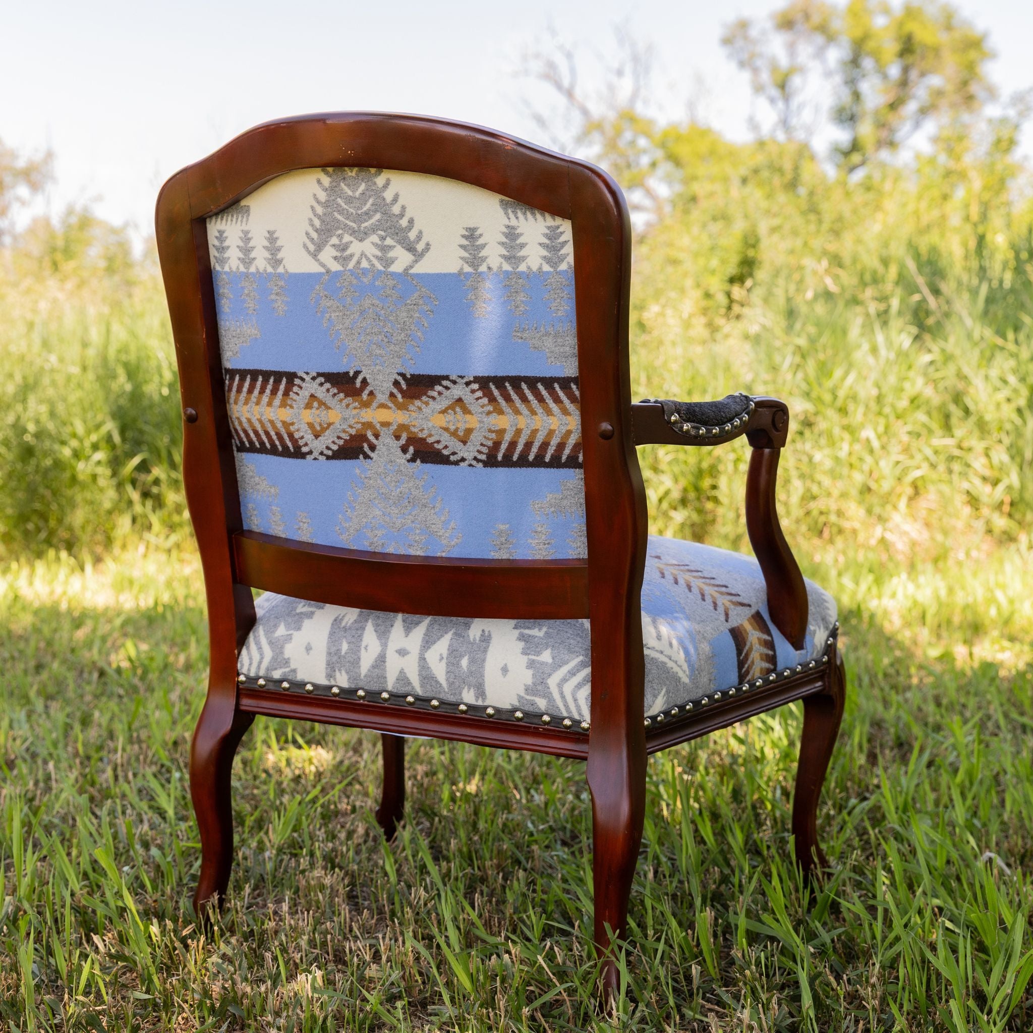 Chair with western patterned backrest and seat in a grassy outdoor setting