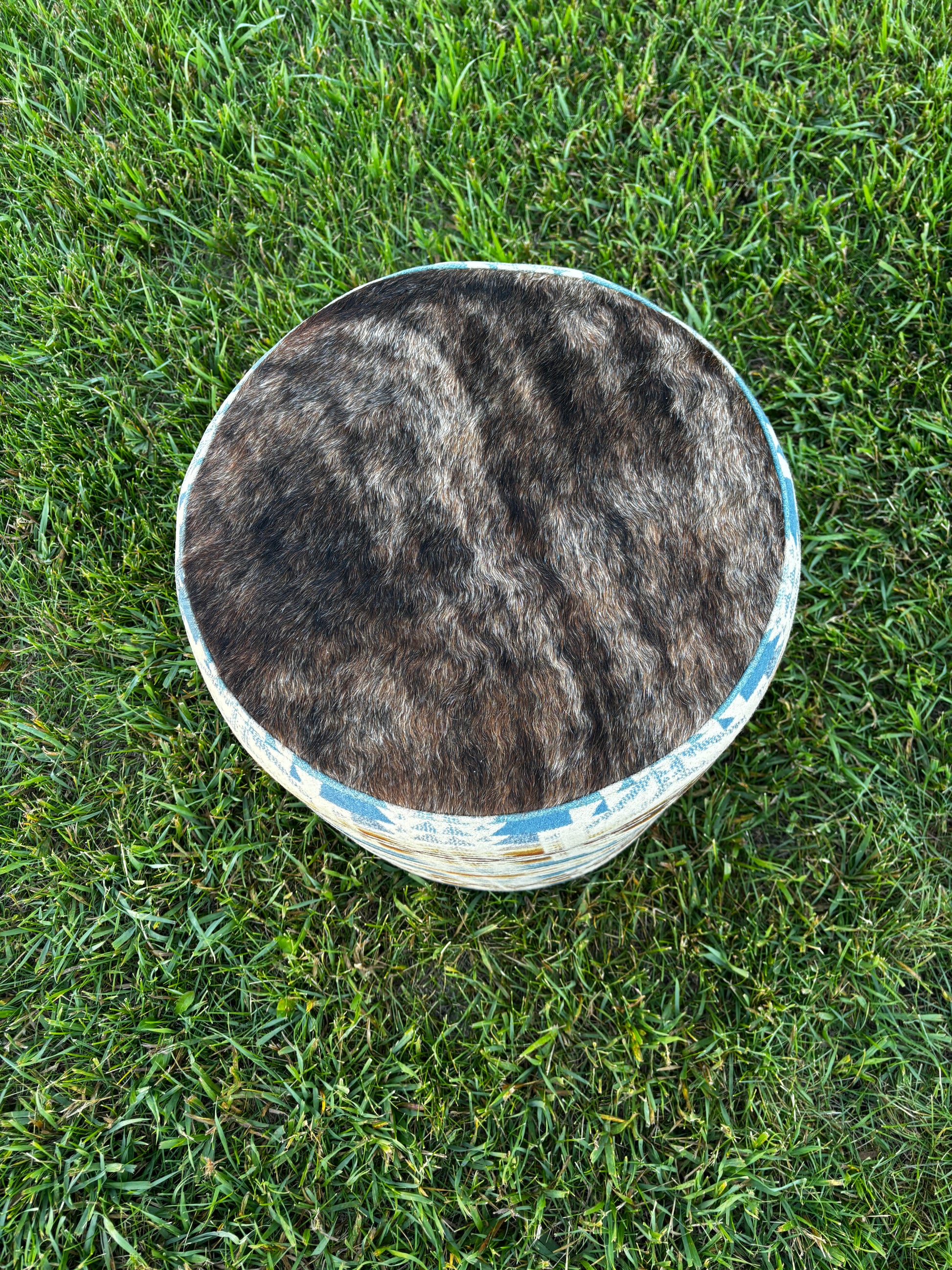Rustic ottoman with authentic hide and Pendleton Shonto Wheatlands fabric photographed in natural outdoor lighting.