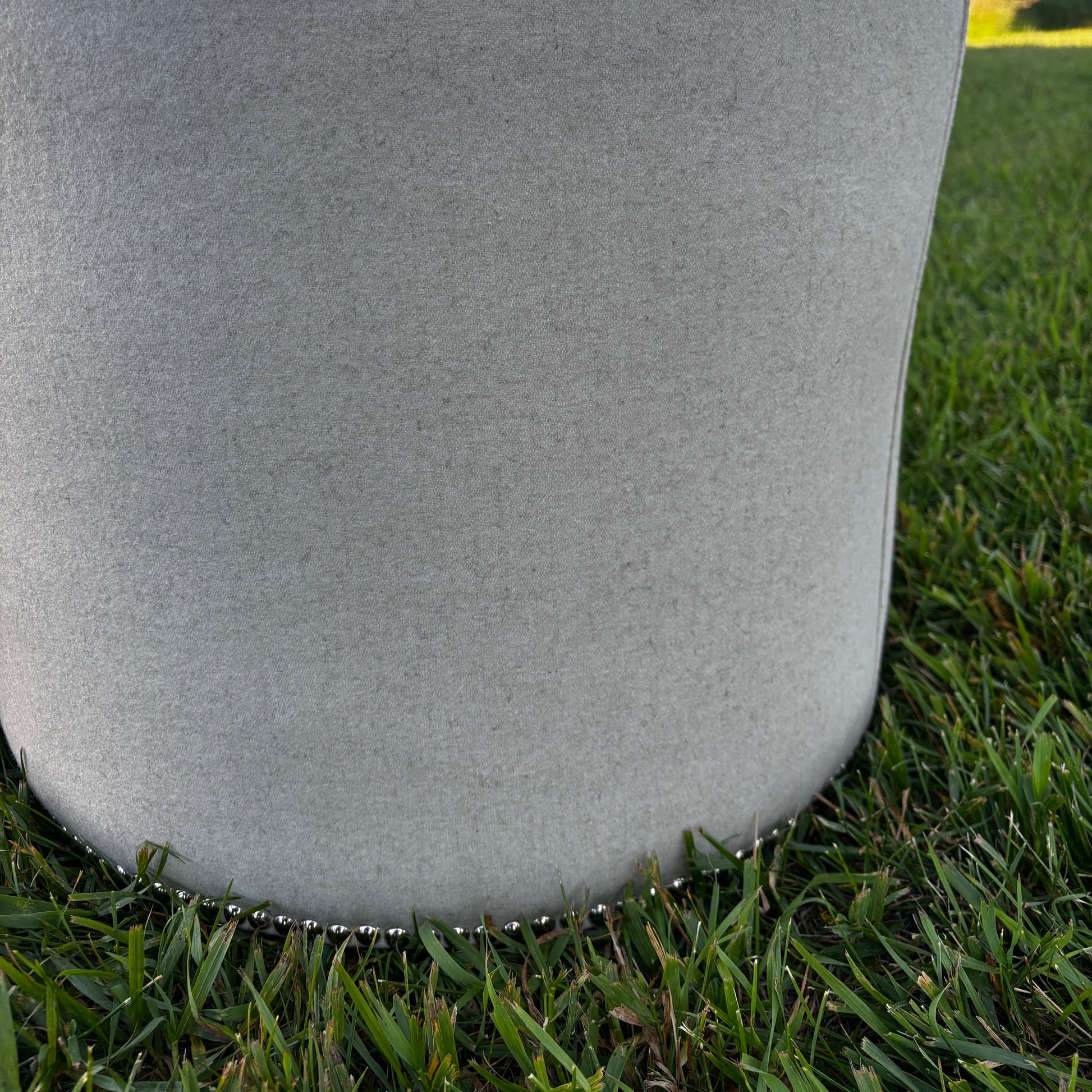 Side outdoor view showing nailhead trim and soft wool fabric of the ottoman