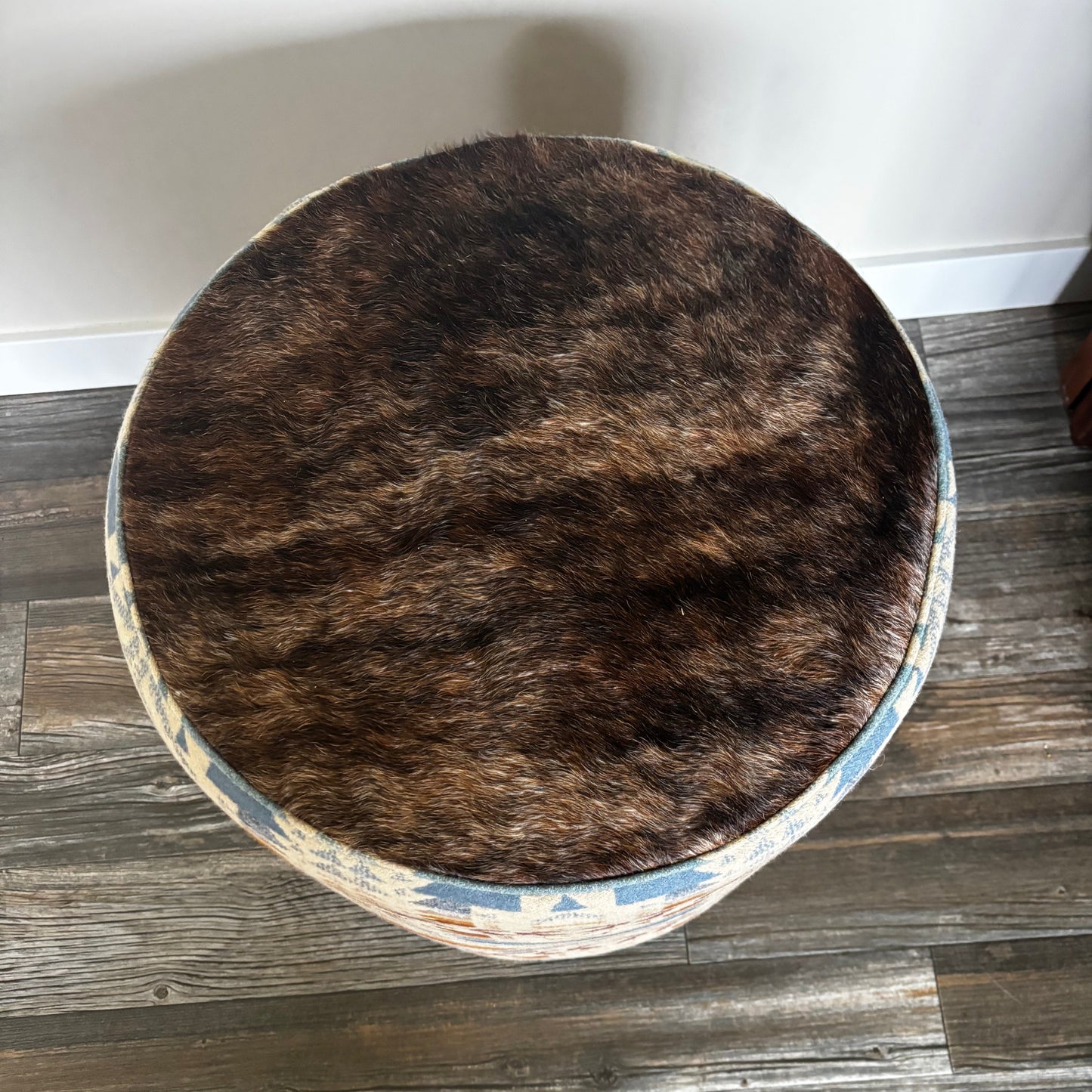 Top view of ottoman showing brown genuine hair-on-hide seat and detailed Pendleton wool fabric sides.