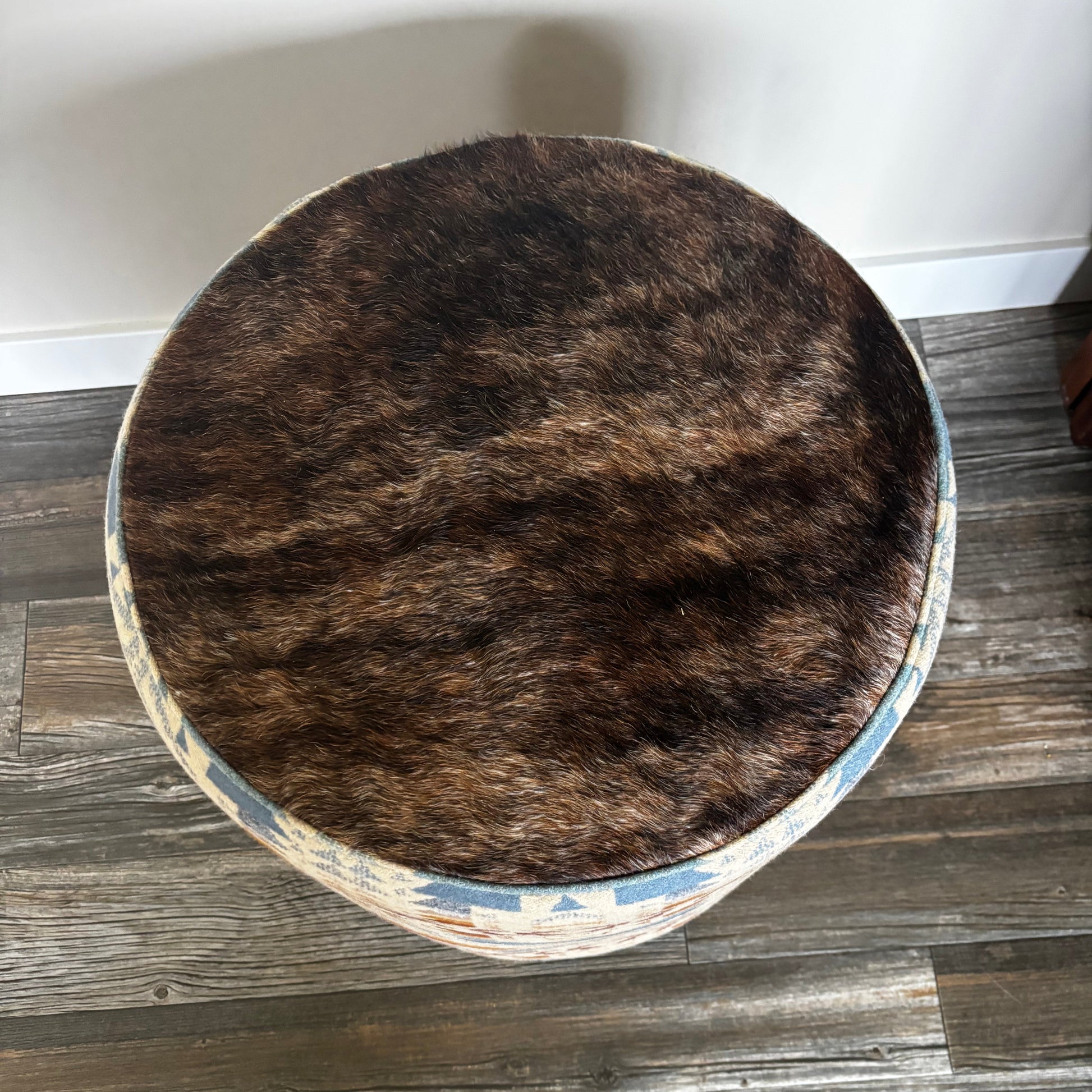 Top view of ottoman showing brown genuine hair-on-hide seat and detailed Pendleton wool fabric sides.